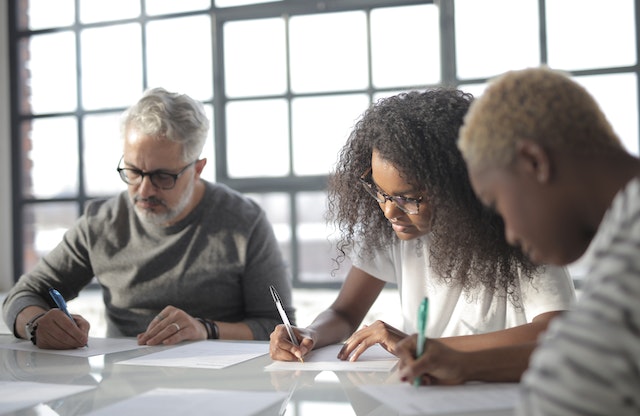 Three focused people working on notes at a conference table